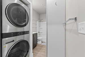 Laundry area featuring stacked washing machine and dryer and light wood-type flooring