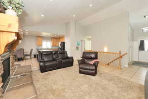 Living room featuring light tile patterned floors, light carpet, a fireplace, high vaulted ceiling, and recessed lighting