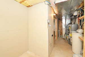 Unfinished below grade area featuring a water softener and water heater