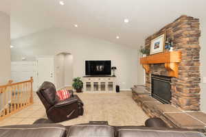 Living area featuring light colored carpet, arched walkways, a fireplace, recessed lighting, and light tile patterned floors