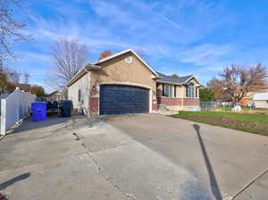 View of front of property featuring brick siding, concrete driveway, a garage, and stucco siding