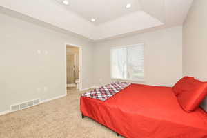 Bedroom featuring a tray ceiling, carpet floors, ensuite bathroom, and recessed lighting
