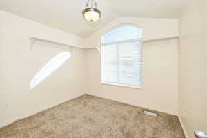 Walk in closet with vaulted ceiling and carpet flooring