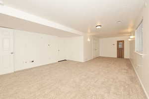 Empty room with light colored carpet and a textured ceiling