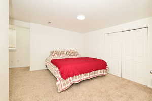Bedroom with carpet, a closet, and a textured ceiling