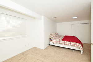 Carpeted bedroom with a closet and a textured ceiling
