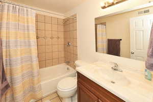 Bathroom featuring shower / bath combo with shower curtain, vanity, and light tile patterned floors