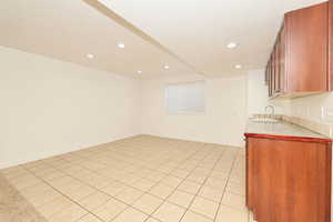 Kitchen featuring light countertops, recessed lighting, light tile patterned flooring, brown cabinetry, and open floor plan