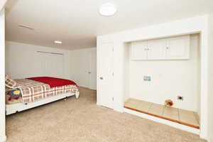 Bedroom featuring light colored carpet, a closet, a textured ceiling, and light tile patterned flooring