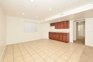 Kitchen featuring light countertops, light tile patterned floors, brown cabinets, and recessed lighting