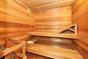 Relaxing sauna featuring wooden ceiling, tile patterned floors, and wood walls