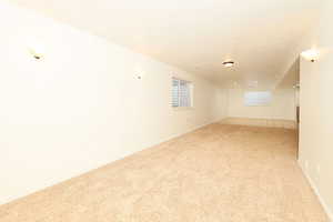 Empty room with light colored carpet and a textured ceiling