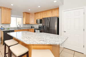 Kitchen with light tile patterned floors, stainless steel appliances, light stone countertops, and recessed lighting