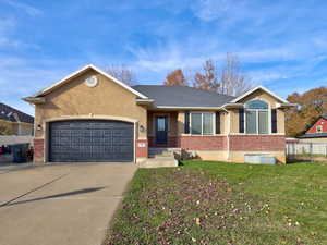 Single story home featuring brick siding, driveway, a garage, and stucco siding