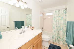 Full bathroom with light tile patterned floors, vanity, and shower / tub combo with curtain