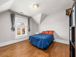 Bedroom featuring wood finished floors and vaulted ceiling