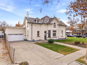 French country style house with a chimney, brick siding, a front yard, and concrete driveway