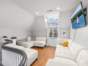 Living room featuring vaulted ceiling, light wood-style floors, and recessed lighting