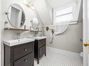 Bathroom featuring two vanities and vaulted ceiling