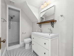 Bathroom featuring a tile shower, double vanity, and light tile patterned floors