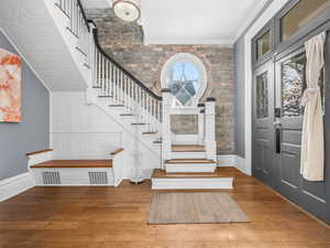 Foyer with wood finished floors, crown molding, and stairway