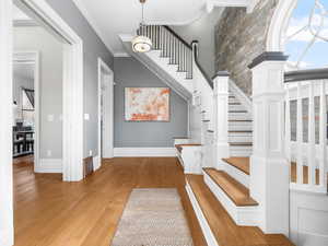 Staircase featuring wood finished floors and ornamental molding