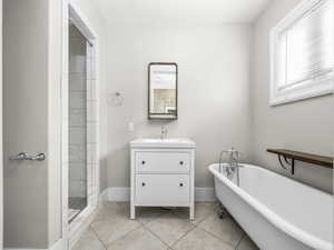 Full bath with vanity, a soaking tub, light tile patterned floors, and a shower stall