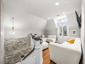 Living room with vaulted ceiling, recessed lighting, and wood finished floors