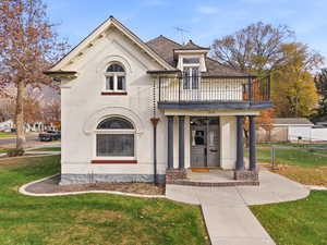 View of front facade featuring brick siding, a porch, and a balcony