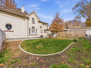 Back of house with a fenced backyard, a chimney, and a mountain view