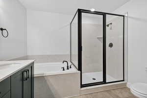 Full bath featuring vanity, a garden tub, a marble finish shower, and light tile patterned flooring