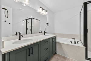 Bathroom with a stall shower, a bath, double vanity, and light tile patterned floors