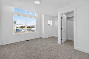 Unfurnished bedroom with a spacious closet and light carpet