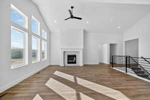 Unfurnished living room with high vaulted ceiling, a tile fireplace, light wood-style floors, recessed lighting, and ceiling fan
