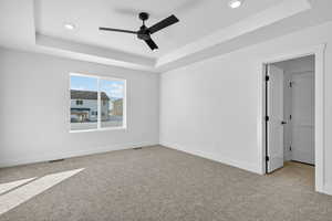 Spare room featuring a tray ceiling, light carpet, a ceiling fan, and recessed lighting