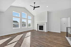 Unfurnished living room featuring high vaulted ceiling, dark wood-style floors, a fireplace, ceiling fan, and recessed lighting