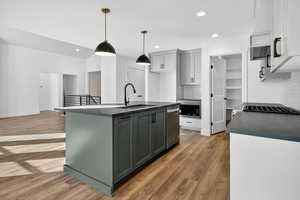Kitchen with decorative backsplash, light wood-style flooring, an island with sink, gray cabinets, and recessed lighting
