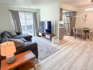 Living area with light wood finished floors and a textured ceiling