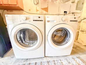 Washroom featuring washer and clothes dryer, concrete floors, and electric panel