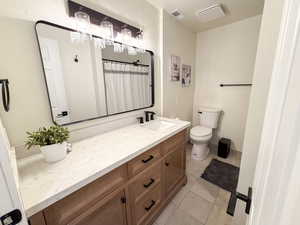 Full bath with curtained shower, vanity, and light tile patterned floors