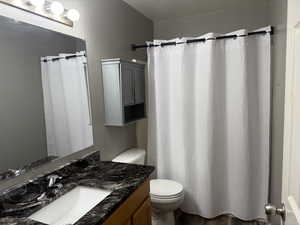 Bathroom with a textured ceiling, vanity, a shower with curtain, and dark wood-type flooring