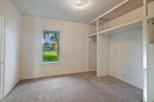 Unfurnished bedroom with carpet flooring, a textured ceiling, and a closet