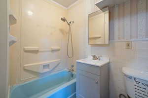 Bathroom with shower / bathtub combination, vanity, wallpapered walls, and tile walls