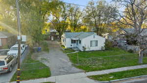 Bungalow-style house featuring a fenced front yard, driveway, and view of wooded area