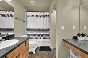 Full bath featuring vanity and dark tile patterned flooring