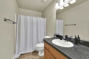 Full bathroom featuring a shower with shower curtain, vanity, and dark tile patterned floors