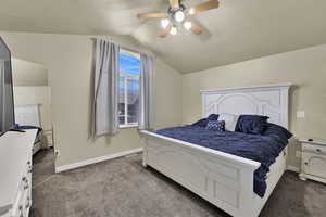Bedroom featuring dark colored carpet, lofted ceiling, and a ceiling fan