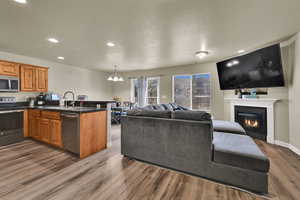 Living area with recessed lighting, a glass covered fireplace, dark wood-style flooring, a textured ceiling, and a chandelier