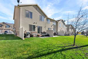 Back of house with a patio area, a residential view, brick siding, and a yard