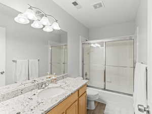 Full bathroom featuring vanity, light wood-style flooring, bath / shower combo with glass door, and a chandelier